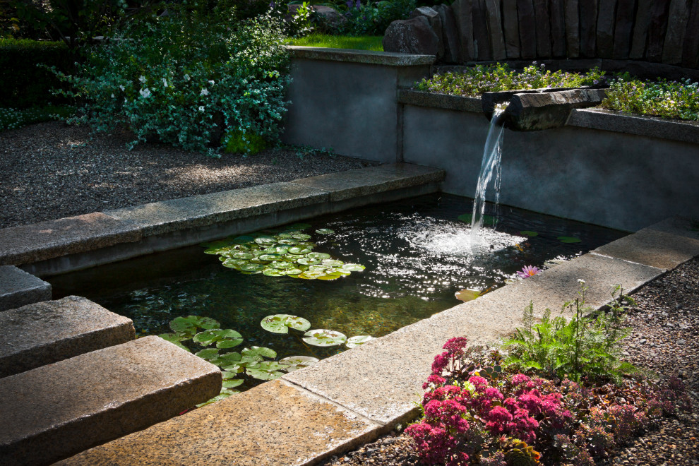 This is an example of a mid-sized contemporary full sun front yard gravel water fountain landscape.
