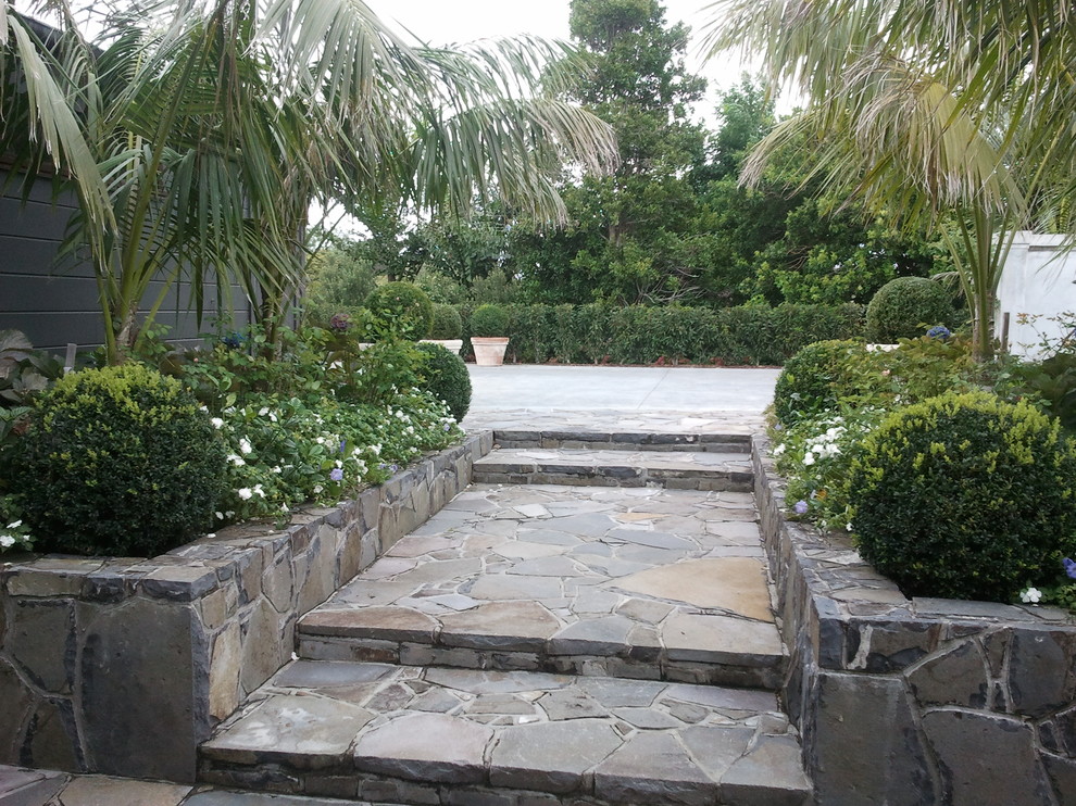 Large rustic back formal garden in Auckland with a potted garden and gravel.