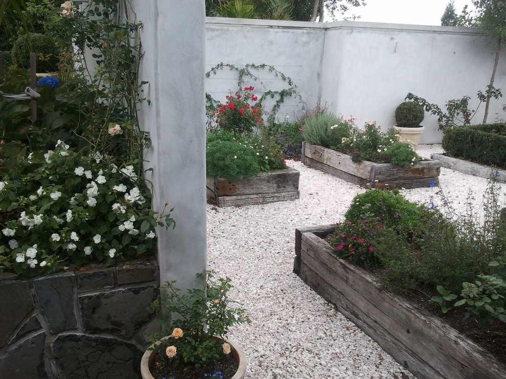 Пример оригинального дизайна: большой регулярный сад на заднем дворе в стиле рустика с растениями в контейнерах и покрытием из гравия