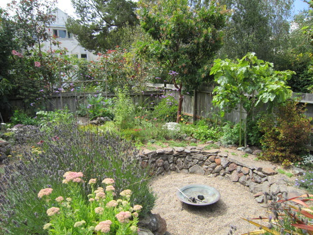 Ejemplo de jardín mediterráneo de tamaño medio en otoño en patio trasero con exposición total al sol, gravilla y brasero