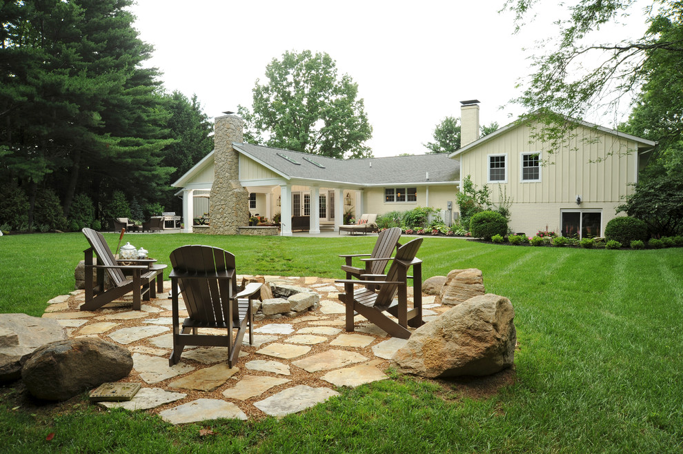 Cette image montre un grand jardin arrière traditionnel avec un foyer extérieur, une exposition ensoleillée et des pavés en pierre naturelle.