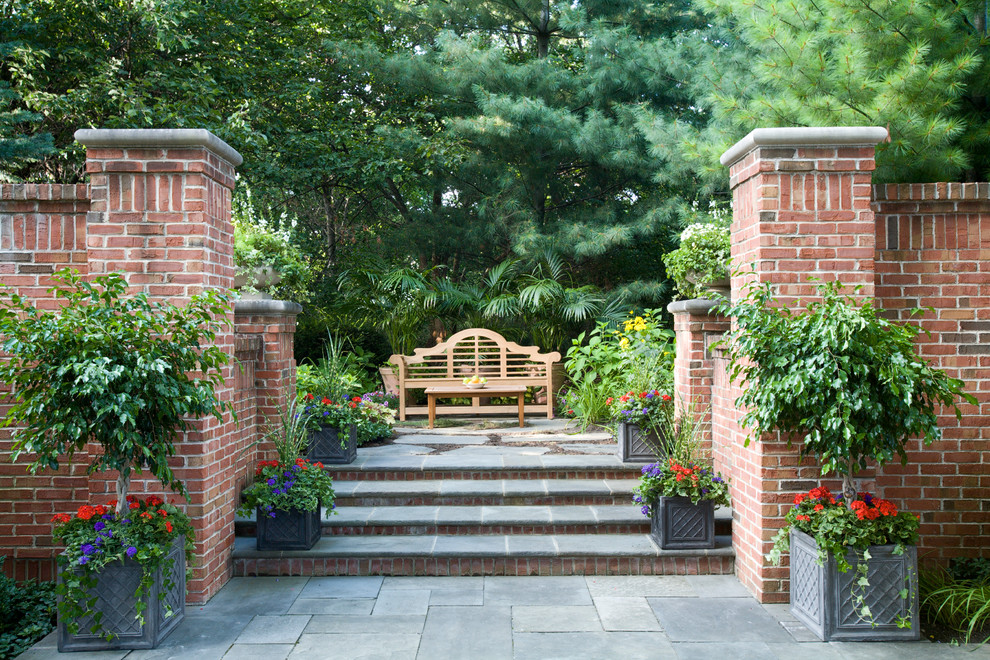 Réalisation d'un jardin arrière tradition avec des pavés en pierre naturelle.