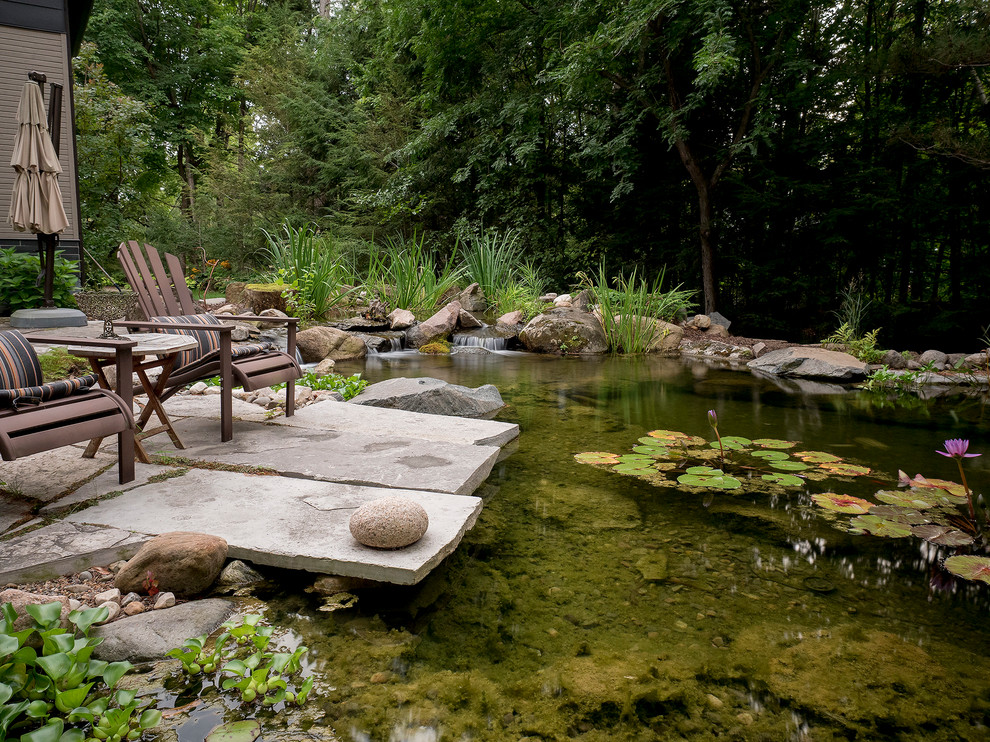 Imagen de jardín vintage extra grande en primavera en patio trasero con estanque, exposición total al sol y adoquines de piedra natural