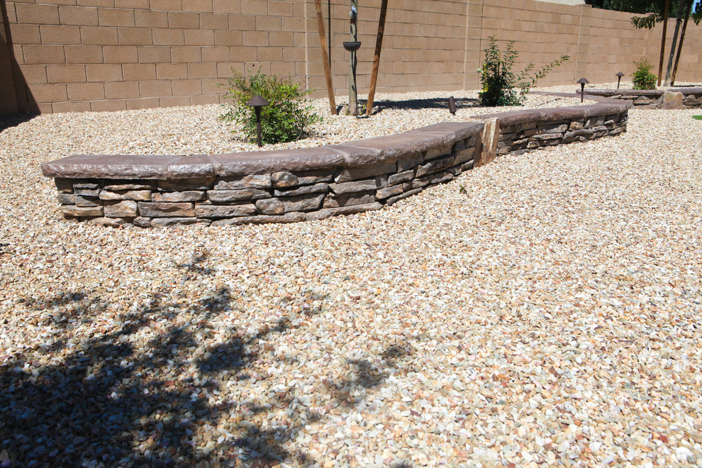На фото: регулярный сад среднего размера на заднем дворе в стиле фьюжн с покрытием из гравия, подпорной стенкой и полуденной тенью с