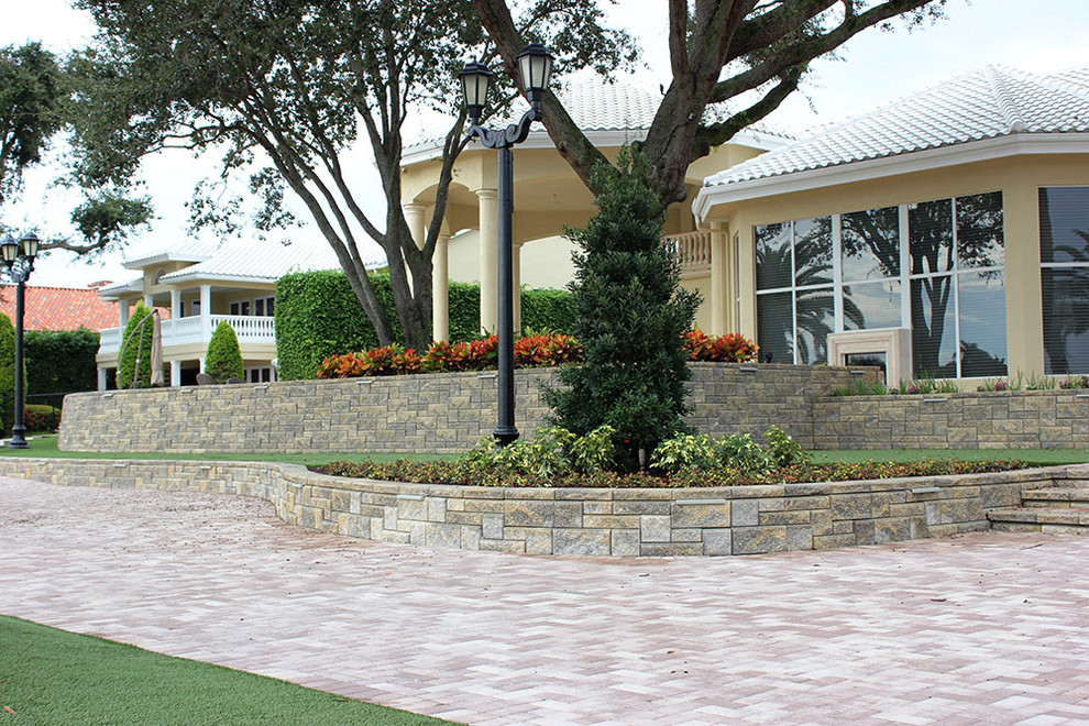 Immagine di un grande giardino contemporaneo dietro casa con un muro di contenimento e pavimentazioni in cemento