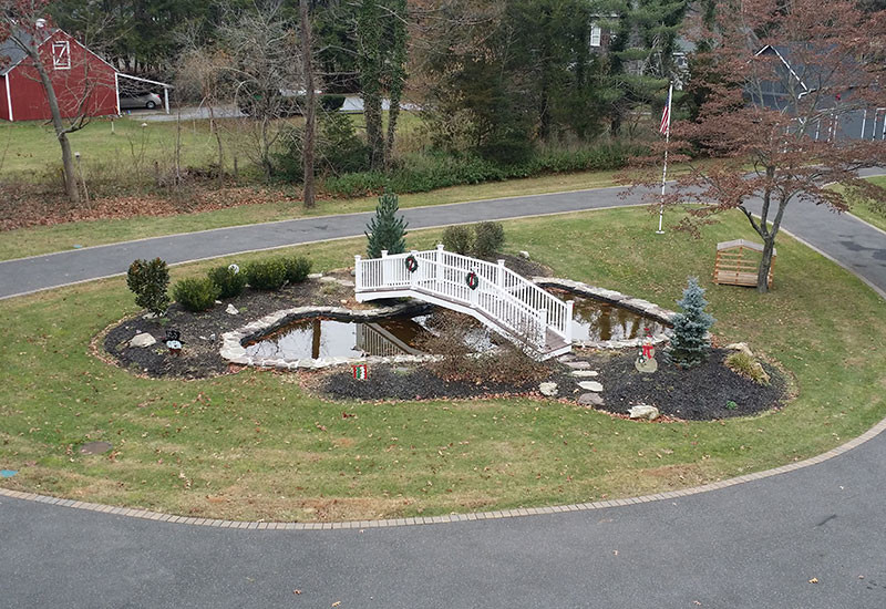 Photo of a large traditional front driveway full sun garden for summer in New York with a pond and natural stone paving.