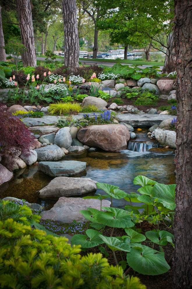 Foto på en mellanstor funkis gårdsplan, med en fontän och naturstensplattor