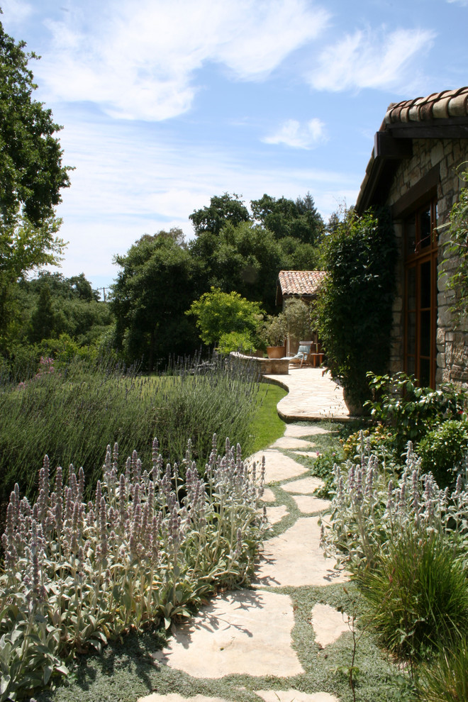 Klassischer Garten hinter dem Haus mit Natursteinplatten und direkter Sonneneinstrahlung in Sonstige
