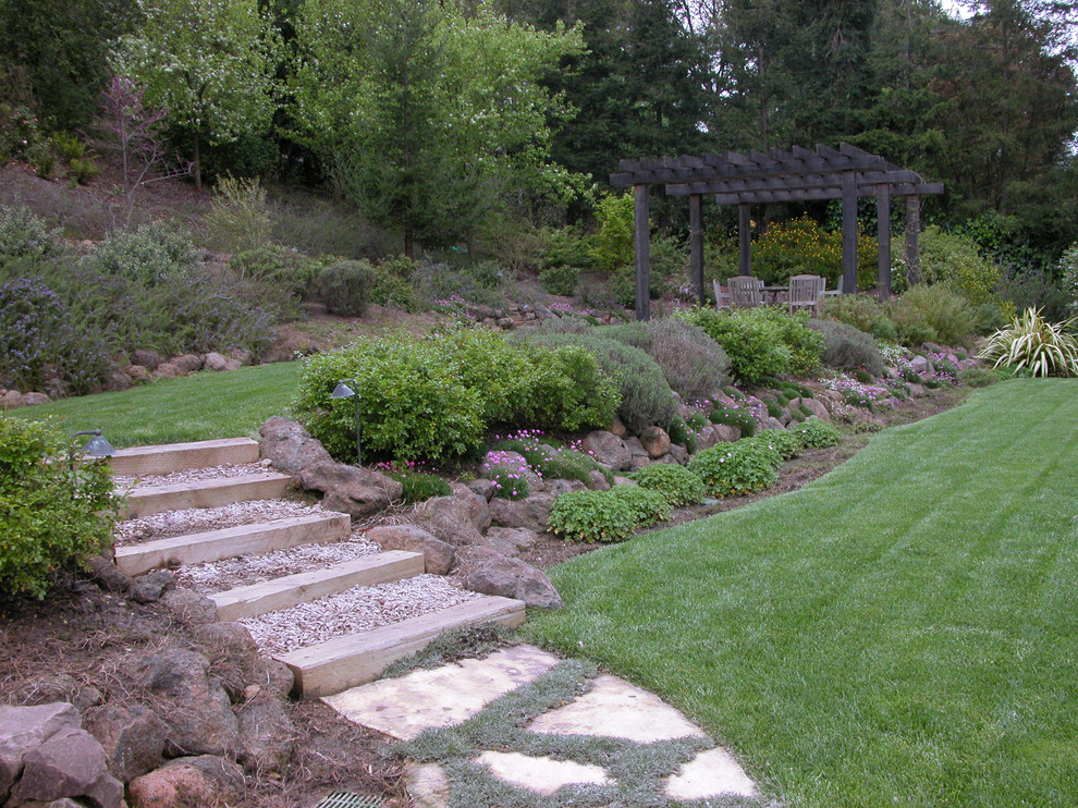 Ejemplo de jardín clásico grande en patio trasero con exposición total al sol y adoquines de piedra natural