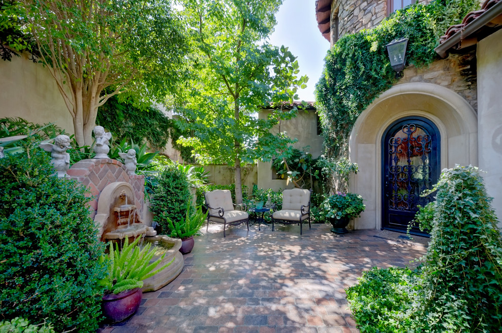 This is an example of a medium sized mediterranean courtyard partial sun garden for spring in San Diego with a garden path and brick paving.