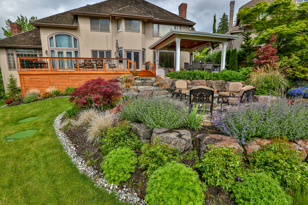 This is an example of a large classic back full sun garden in Seattle with natural stone paving.