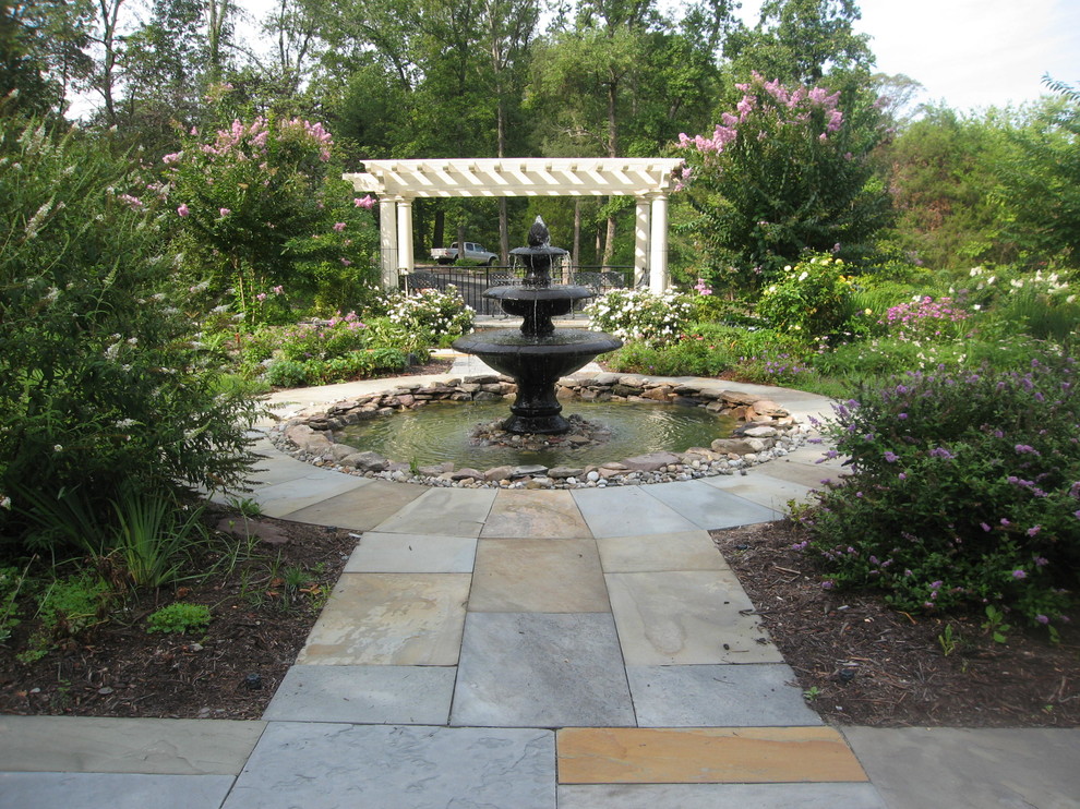 Esempio di un ampio giardino formale chic esposto in pieno sole nel cortile laterale in primavera con fontane e pavimentazioni in pietra naturale