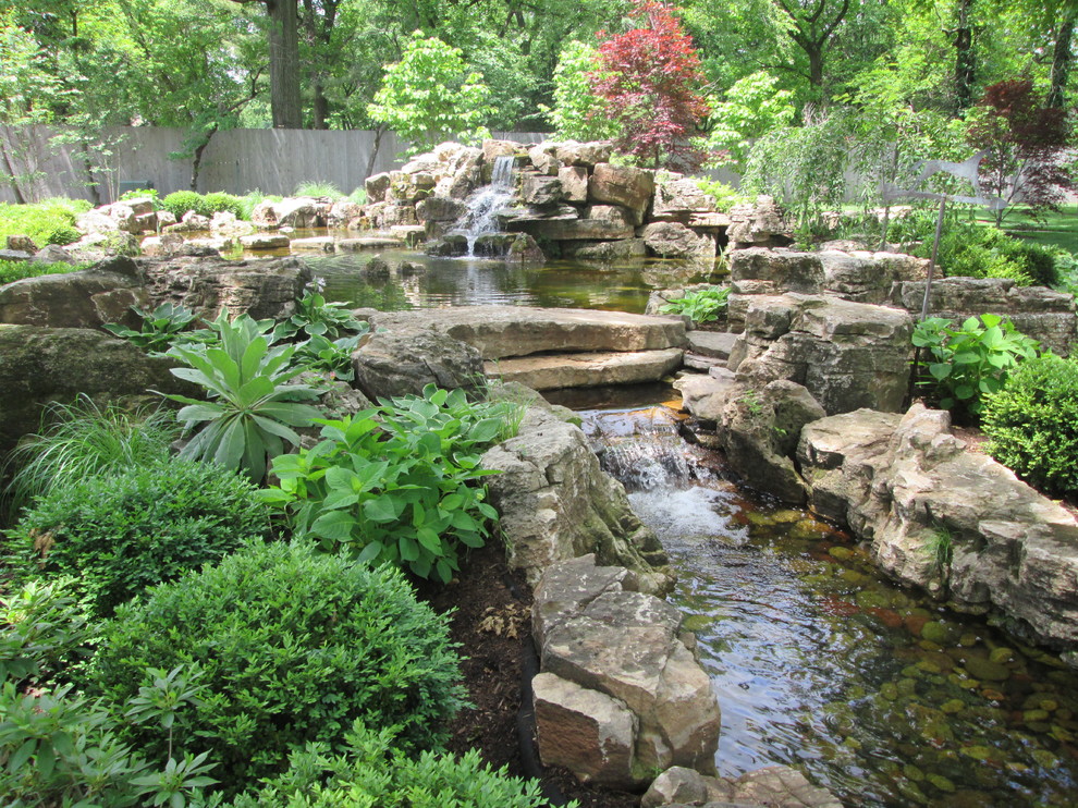 Aménagement d'un très grand jardin arrière classique au printemps avec un bassin et une exposition partiellement ombragée.