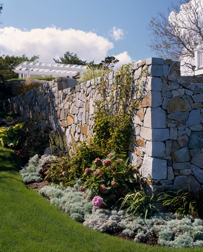 На фото: большой солнечный, летний участок и сад на боковом дворе в морском стиле с подпорной стенкой, покрытием из каменной брусчатки и хорошей освещенностью