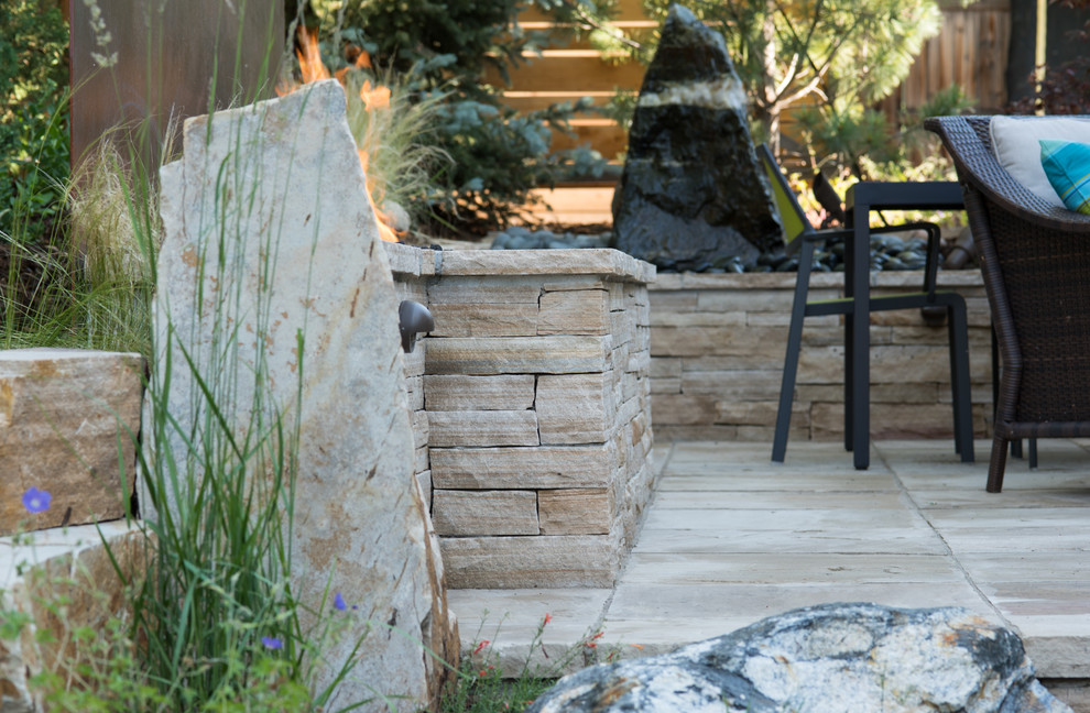 Réalisation d'un jardin arrière design de taille moyenne avec un foyer extérieur et des pavés en pierre naturelle.
