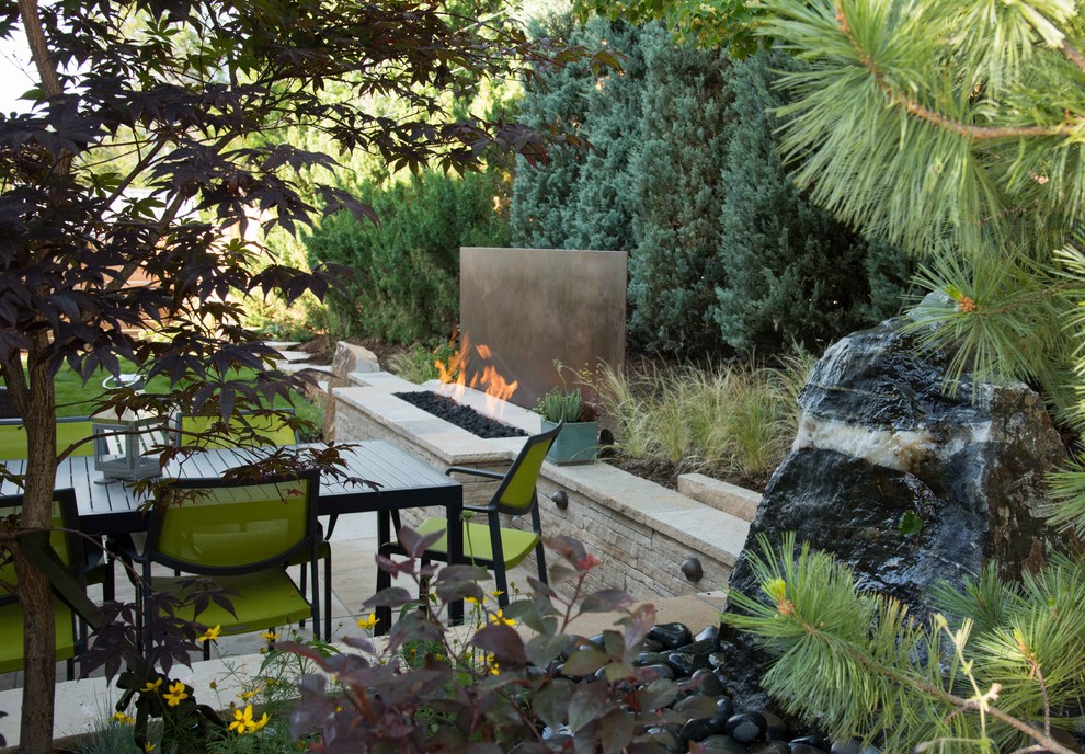Ejemplo de jardín actual de tamaño medio en patio trasero con brasero y adoquines de piedra natural