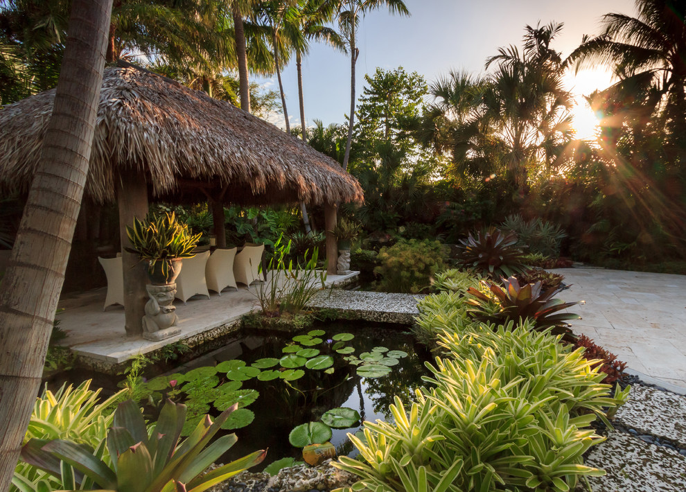 Idéer för att renovera en stor tropisk trädgård i delvis sol längs med huset, med en fontän