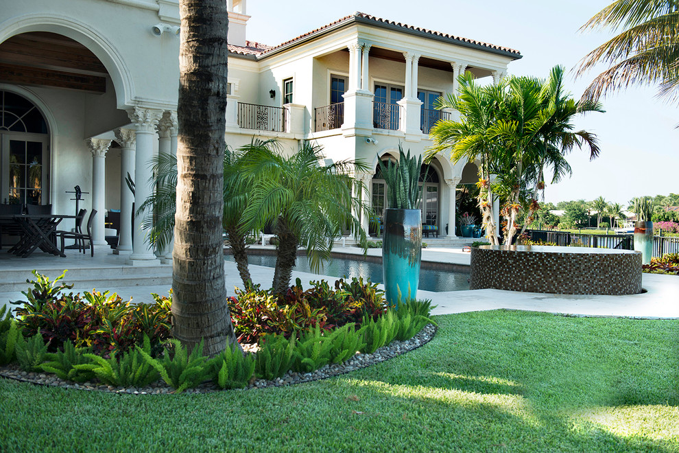 Photo of a large world-inspired back partial sun garden in Miami with a potted garden and natural stone paving.