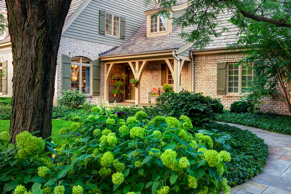 Photo of a mid-sized traditional shade front yard stone landscaping in Chicago for summer.