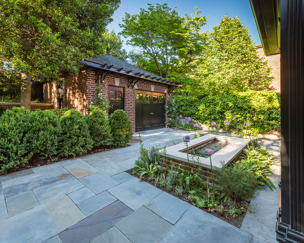 Photo of a classic back driveway partial sun garden in DC Metro with a water feature and natural stone paving.