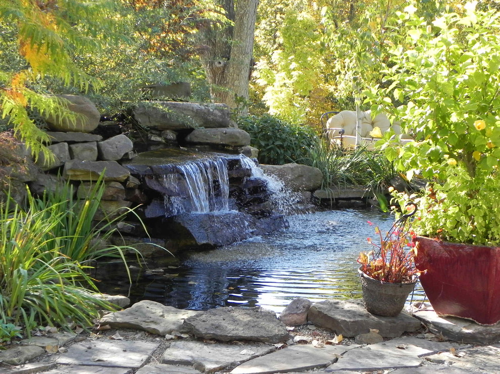 Imagen de jardín tradicional grande en patio trasero con jardín francés, estanque, exposición parcial al sol y adoquines de piedra natural