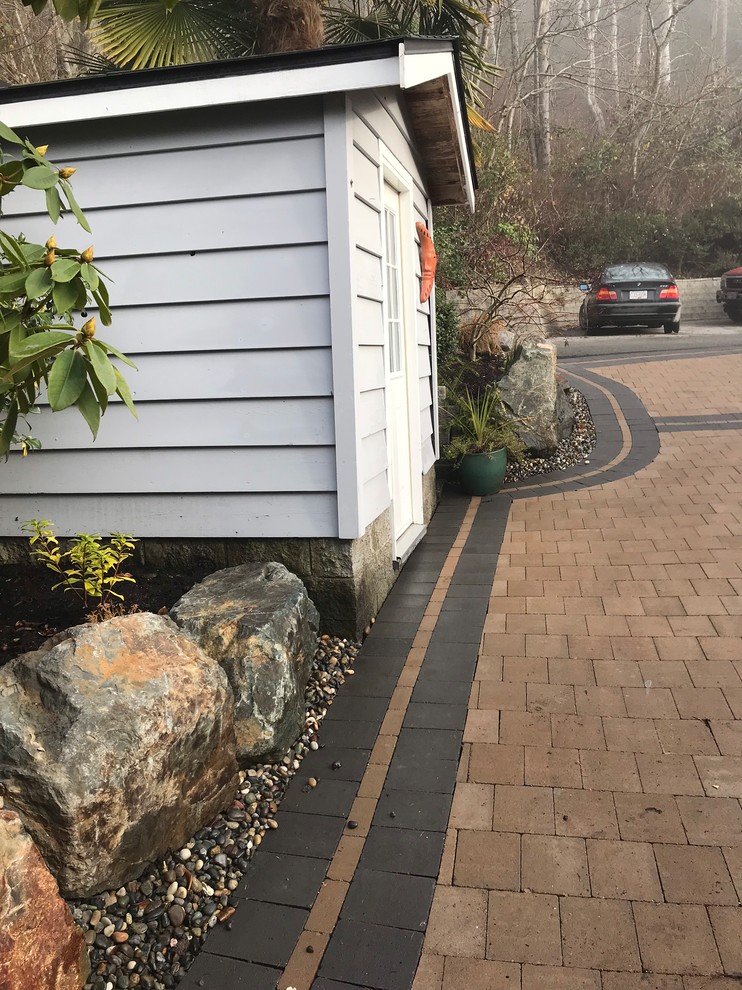 Mittelgroßer Uriger Gartenweg im Frühling, hinter dem Haus mit Auffahrt, direkter Sonneneinstrahlung und Natursteinplatten in Vancouver