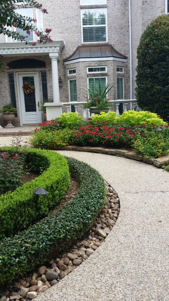 Diseño de jardín clásico extra grande en verano en patio delantero con exposición parcial al sol y adoquines de piedra natural