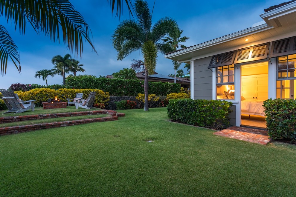 Maritimer Garten hinter dem Haus mit Feuerstelle, direkter Sonneneinstrahlung und Pflastersteinen in Hawaii