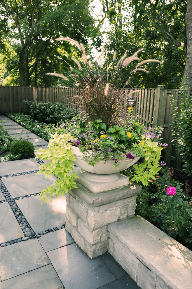 Aménagement d'un jardin latéral classique avec une exposition partiellement ombragée et des pavés en pierre naturelle.