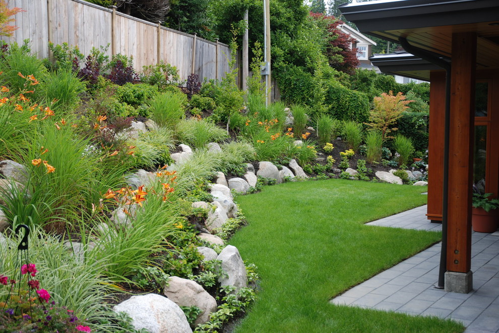 Photo of a large contemporary full sun backyard stone formal garden in Vancouver.