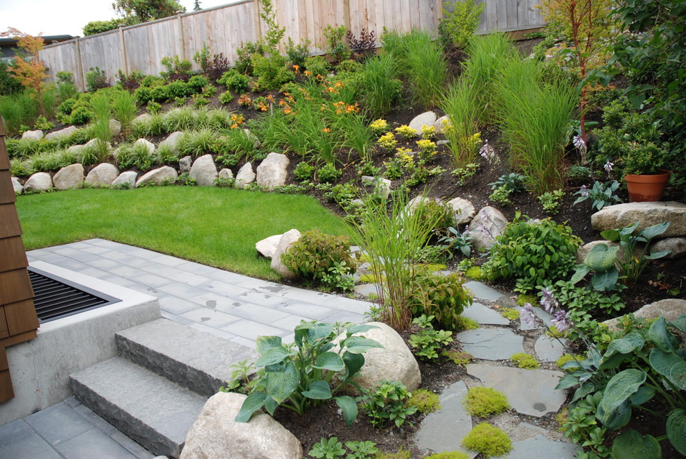 Inspiration pour un grand jardin arrière design avec une exposition ensoleillée et des pavés en pierre naturelle.