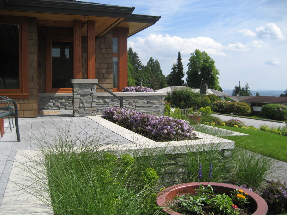 Design ideas for a large contemporary front driveway full sun garden in Vancouver with a retaining wall and natural stone paving.
