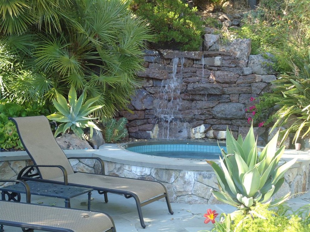 Imagen de jardín clásico renovado de tamaño medio en patio trasero con fuente, exposición parcial al sol y adoquines de piedra natural