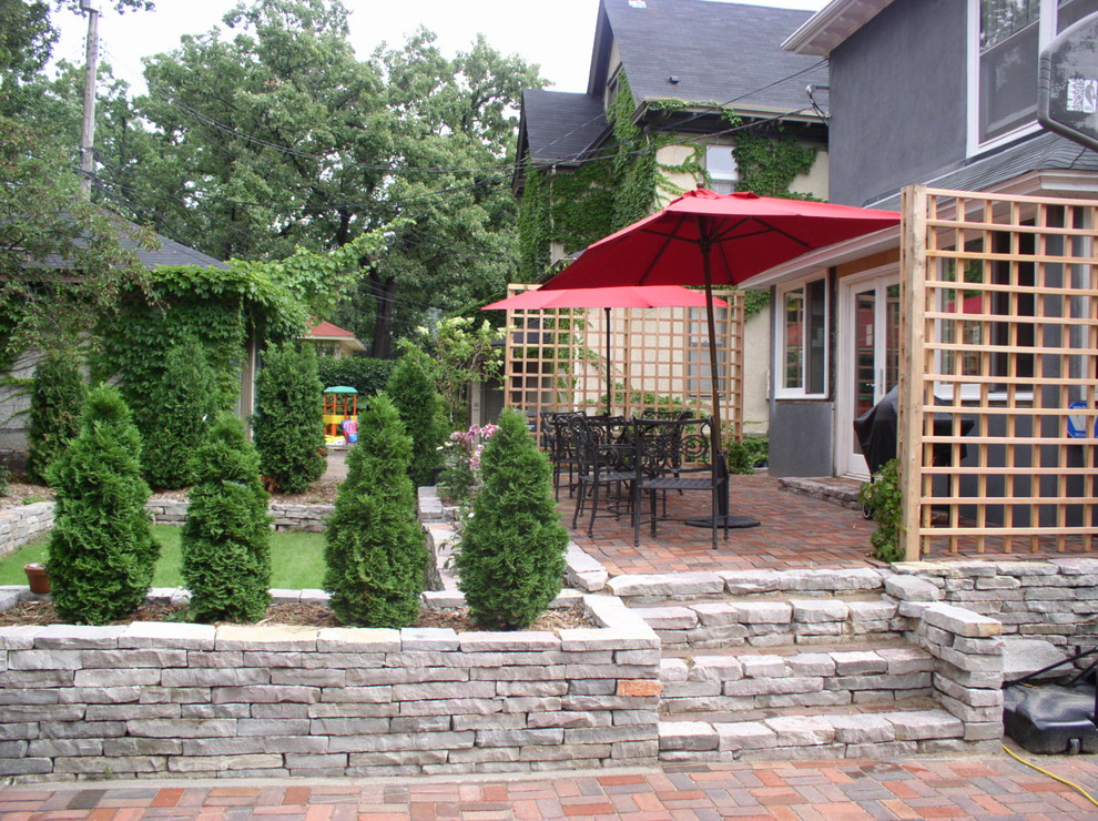 Inspiration for a large classic back driveway full sun garden in Minneapolis with a retaining wall and brick paving.