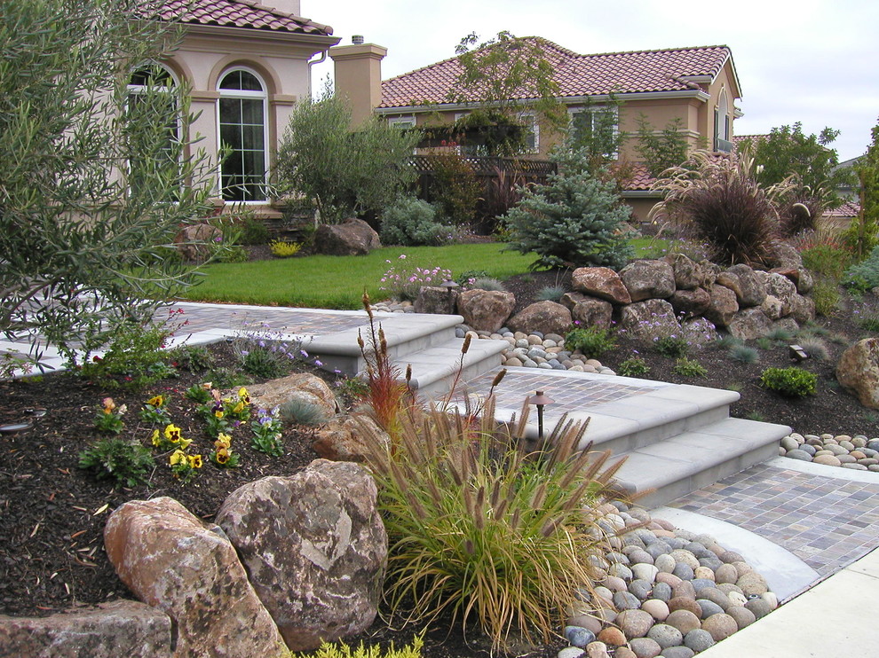 Пример оригинального дизайна: участок и сад на переднем дворе в стиле фьюжн с подпорной стенкой