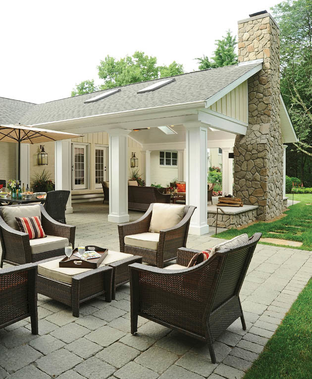 Immagine di un ampio patio o portico classico dietro casa con un focolare e pavimentazioni in mattoni
