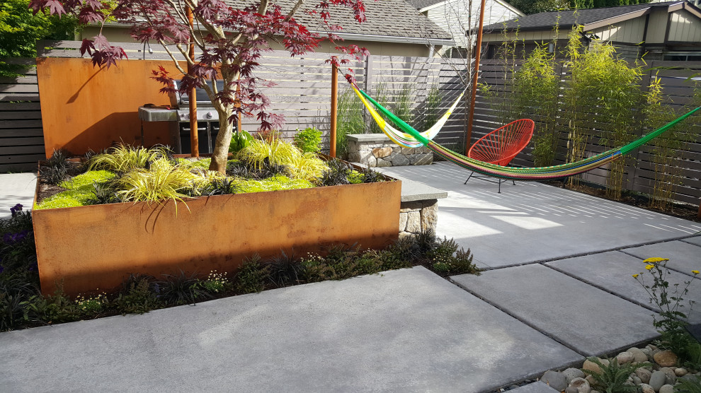 Foto di un giardino design esposto in pieno sole dietro casa in autunno con pavimentazioni in cemento e recinzione in legno