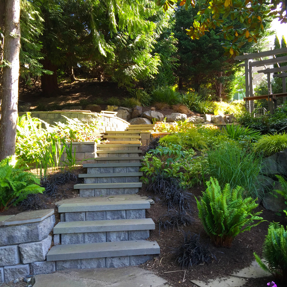 This is an example of a mid-sized traditional drought-tolerant and partial sun backyard stone retaining wall landscape in Seattle.
