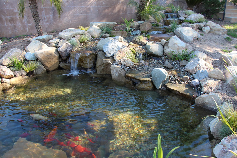 Exemple d'un jardin à la française arrière sud-ouest américain de taille moyenne et au printemps avec un bassin, une exposition ensoleillée et des pavés en pierre naturelle.