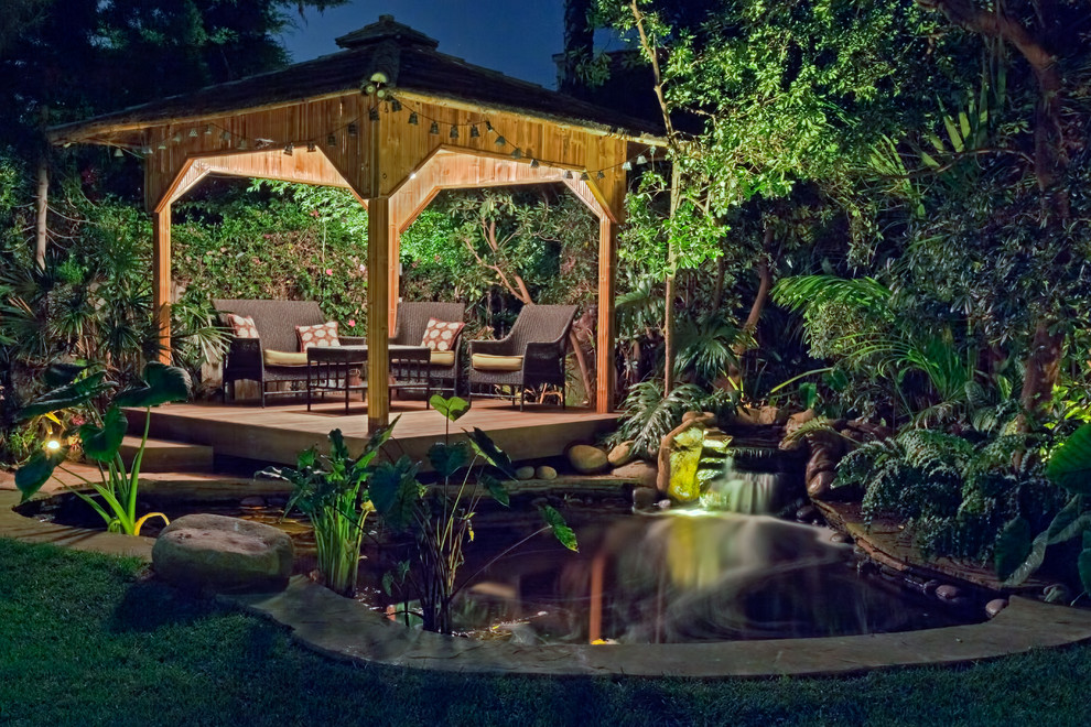 Modelo de jardín tropical grande en patio trasero con estanque y exposición reducida al sol