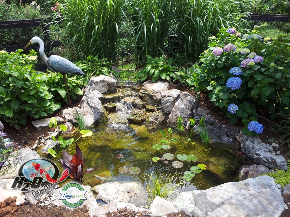 Immagine di un grande laghetto da giardino classico esposto in pieno sole dietro casa con pacciame