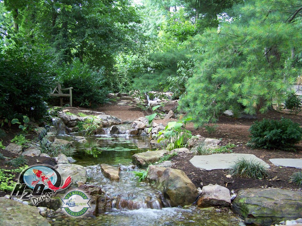 Aménagement d'un grand jardin arrière classique avec un bassin, une exposition ensoleillée et des pavés en pierre naturelle.