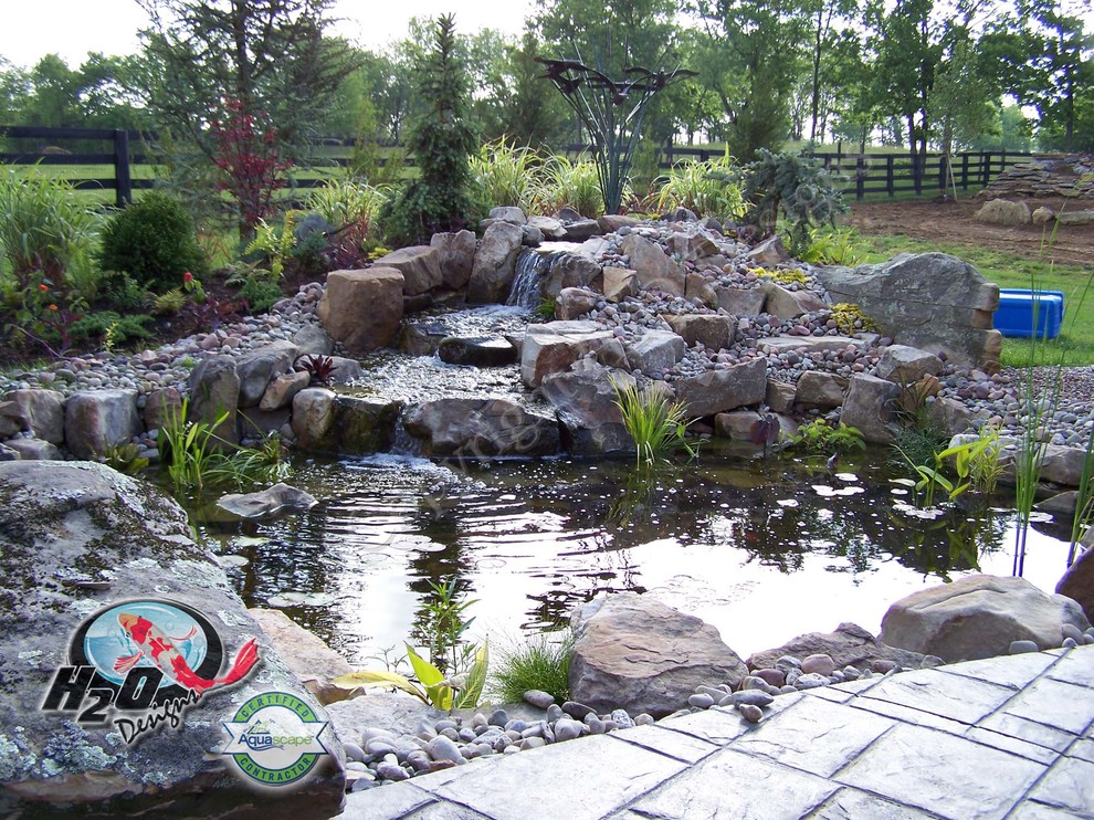 Immagine di un grande laghetto da giardino classico esposto in pieno sole dietro casa con pavimentazioni in pietra naturale