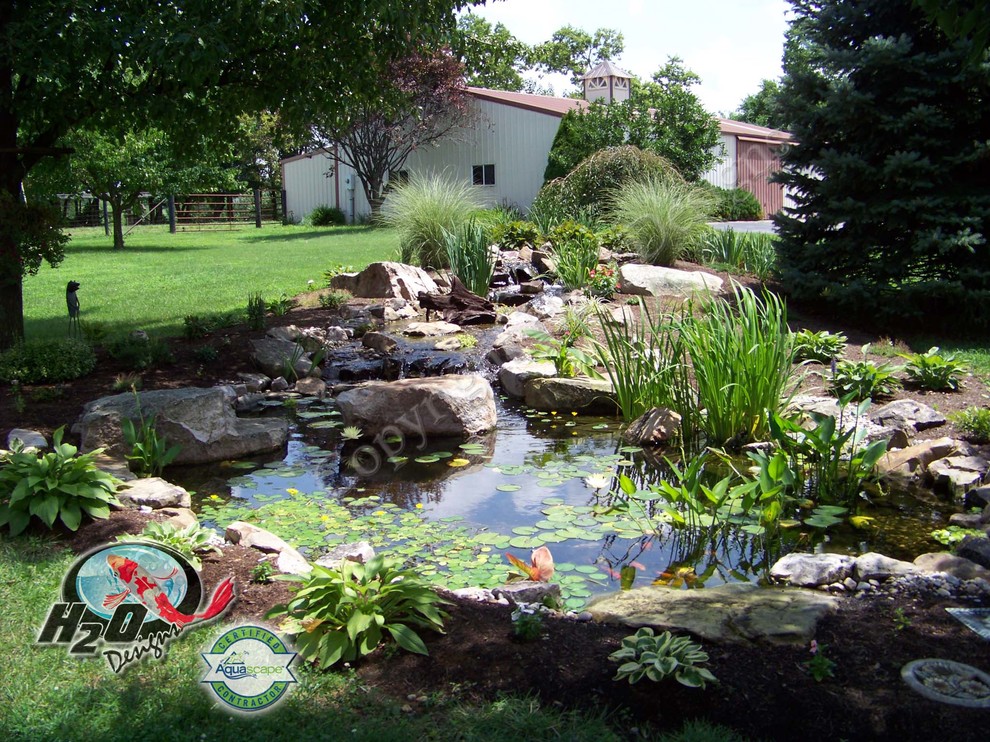 Modelo de jardín clásico grande en patio trasero con estanque, exposición total al sol y mantillo