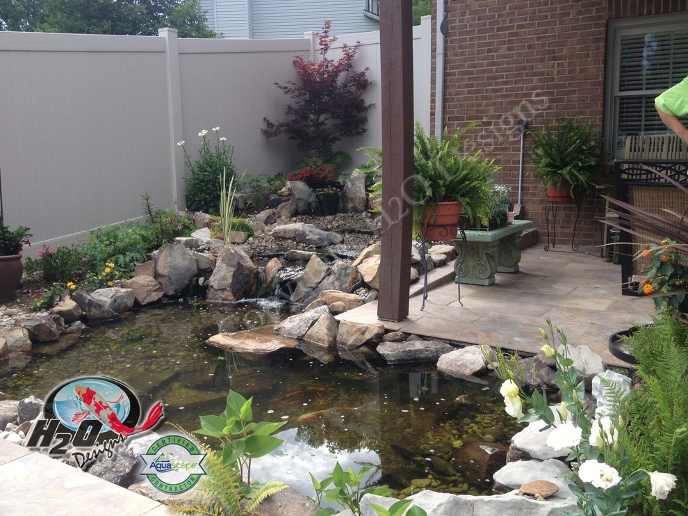 На фото: большой солнечный сад с прудом на заднем дворе в классическом стиле с хорошей освещенностью и покрытием из каменной брусчатки