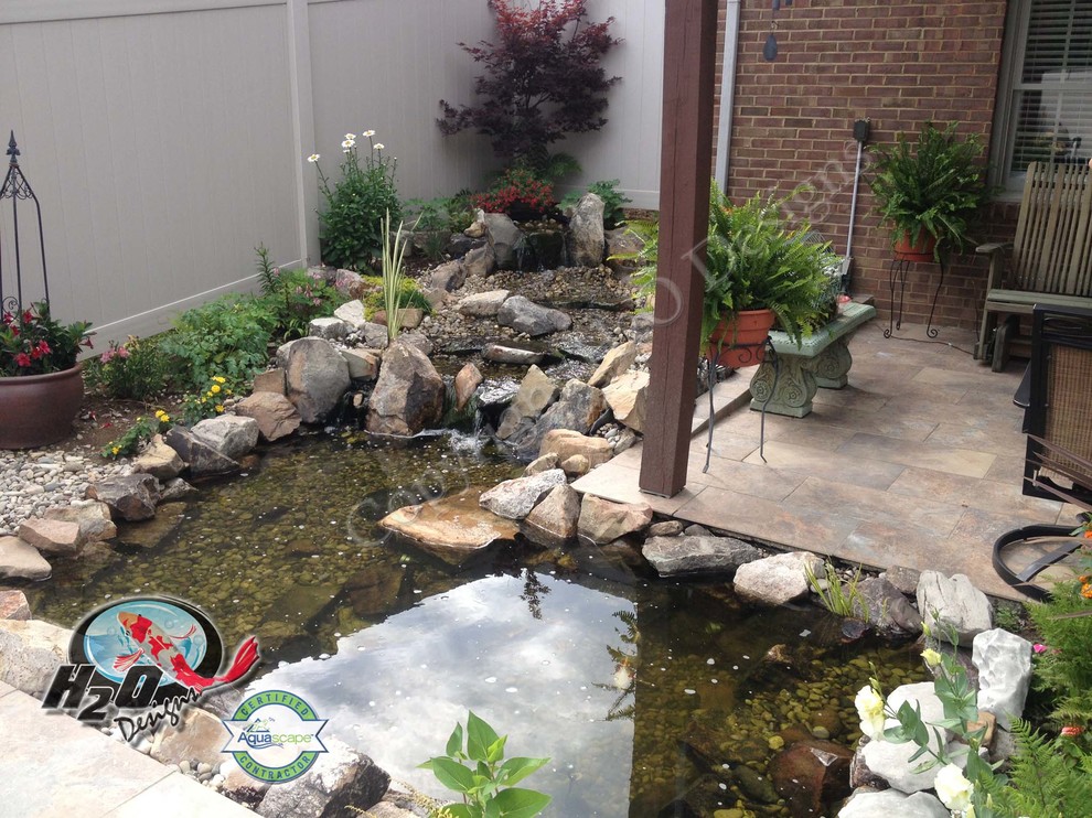 This is an example of a large traditional full sun backyard stone pond in Louisville.