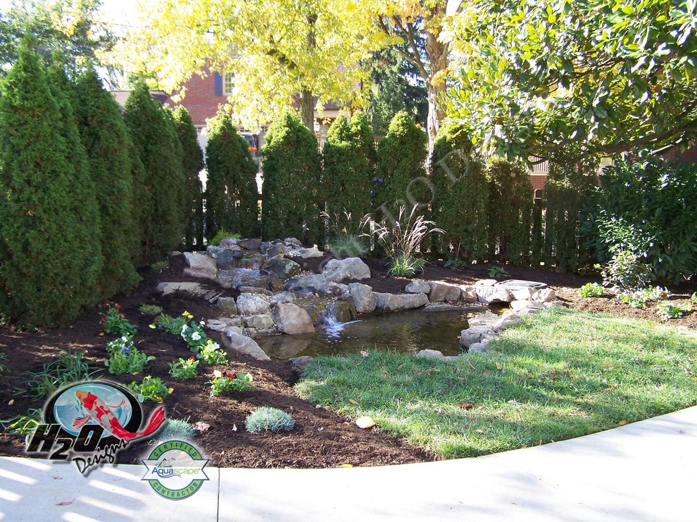 Photo of a large traditional full sun backyard concrete paver pond in Louisville.