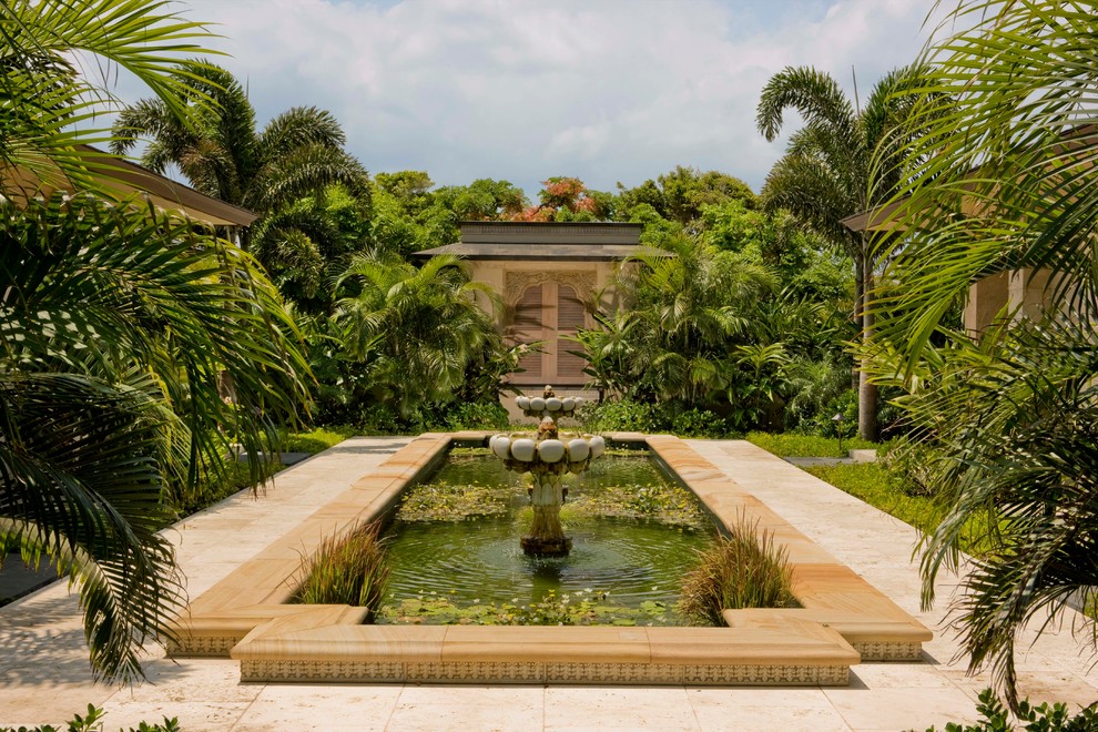 Foto på en tropisk gårdsplan i full sol, med en fontän