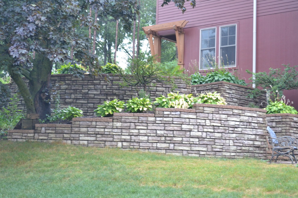 Photo of a mid-sized rustic shade backyard brick retaining wall landscape in Milwaukee for summer.
