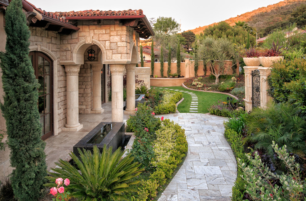 На фото: регулярный сад в средиземноморском стиле с садовой дорожкой или калиткой с